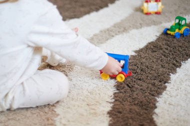 Küçük iki yaşında çocuk çocuk oyuncak araba katta evde halı üzerinde oynamaktan eller. Seçici odak araba ile alan sığ derinliği. Deneyim eğitim konsepti ile öğrenme.