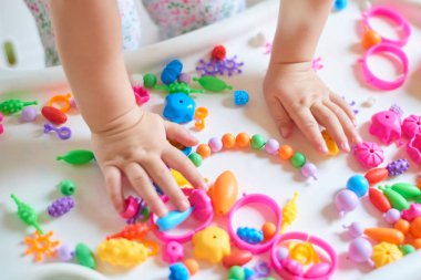 Çocuğun Ellerin masada renkli plastik tuğla ile oynarken kapatın. Eğleniyor ve parlak Oluşturucu tuğla dışında bina toddler. Erken öğrenme. Şerit arka plan. Oyuncaklar geliştirilmesi