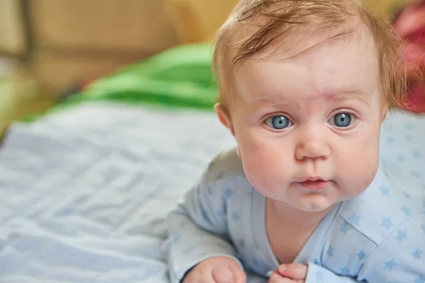 Niedliches Baby auf blauem Bettzeug. — Stockfoto