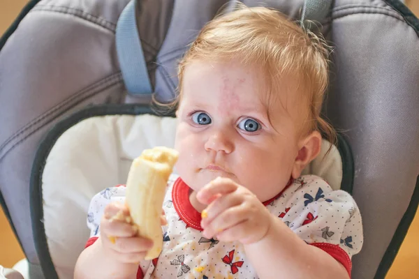 Bebé rubio comiendo plátano — Foto de Stock