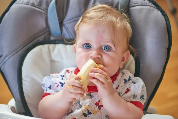 Blond baby eating banana — Stock Photo, Image