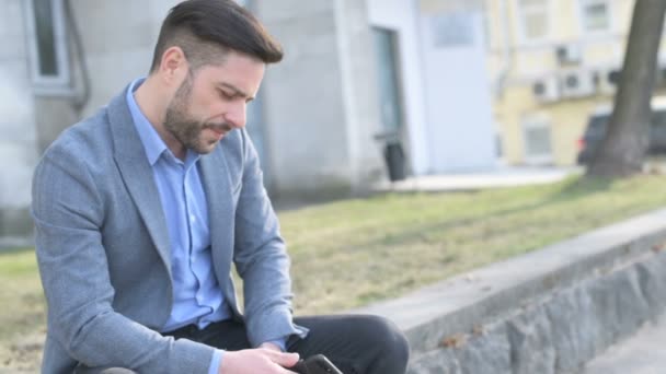 Беспокойный бизнесмен со смартфоном — стоковое видео