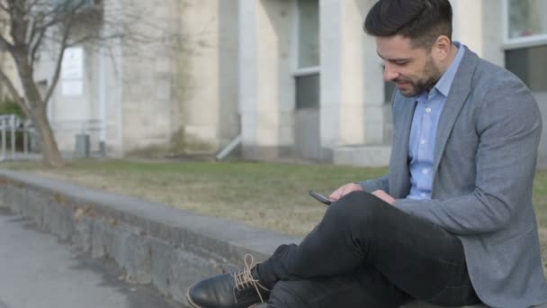 Sonriente y complacido hombre de negocios usando un smartphone — Vídeos de Stock