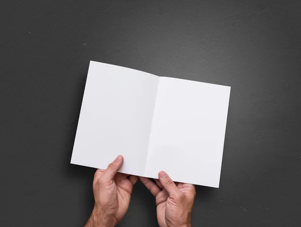 El hombre sostiene en las manos folleto en blanco abierto . — Foto de Stock