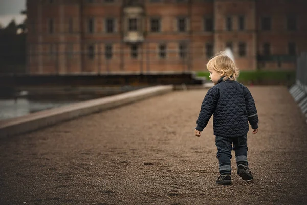 小男孩正走在通往一座旧建筑的土路上 — 图库照片