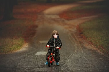 3 yaşındaki çocuk sonbaharda parkta kırmızı bisiklete biniyor.