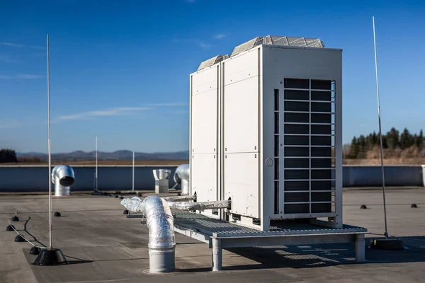 Air vents on the roof of building in functional and operational condition. Around are seen vent pipes and lightning rods. Sky is blue and the background is slightly blurred, focus on ventilation unit.