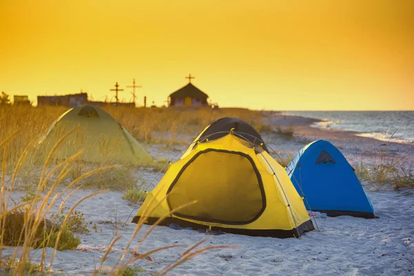 Seaside landscape - sunrise on the seashore with tent camp against the background of an Orthodox Skete