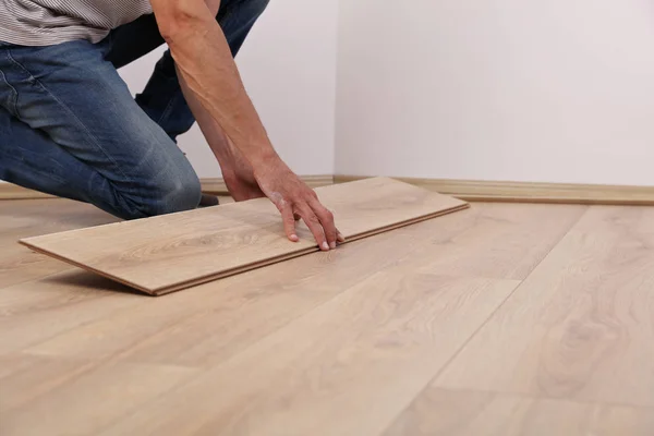Man installing new laminated wooden floor close up
