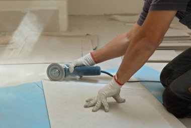 İşçi seramik fayansları dairesel testereyle kesiyor.