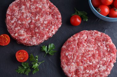 Siyah arka planda çiğ hamburgerler. Yemek fotoğrafçılığı, aşçılık konsepti
