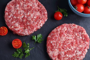 Siyah arka planda çiğ hamburgerler. Yemek fotoğrafçılığı, aşçılık konsepti