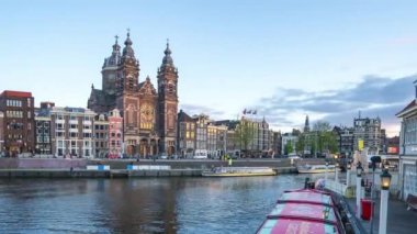 Amsterdam Kanalı 'nın ve Hollanda' nın Amsterdam kentindeki Aziz Nicholas Kilisesi 'nin günden geceye hızlandırılmış videosu..