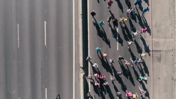 Pie de zángano aéreo 4K. Maratón corriendo por la calle. Siguiendo cámara. Vista superior de cerca — Vídeo de stock
