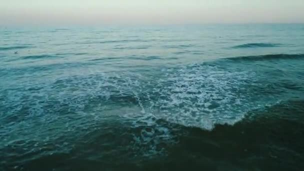 Εναέριο κηφήνα πλάνα. Πετούν πάνω από τα μπλε κύματα της θάλασσας στο βράδυ — Αρχείο Βίντεο