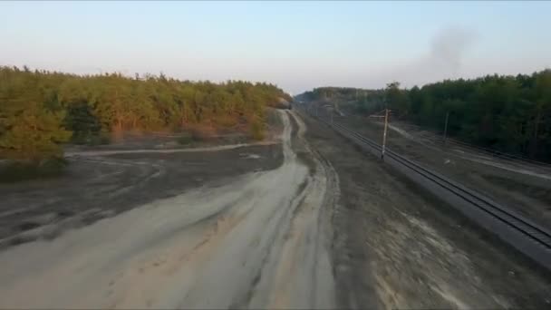 Vue sur les courses de drones. Survolez la route de poussière dans la forêt au coucher du soleil. Plan dynamique — Video