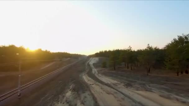Vue sur les courses de drones. Survolez la route de poussière dans la forêt au coucher du soleil. Plan dynamique — Video