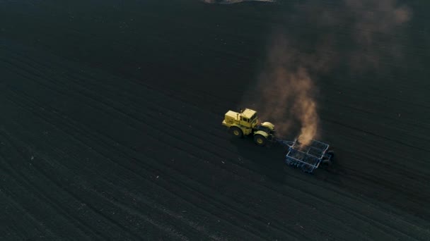 Трактор на большом коричневом поле готовит почву для посева . — стоковое видео