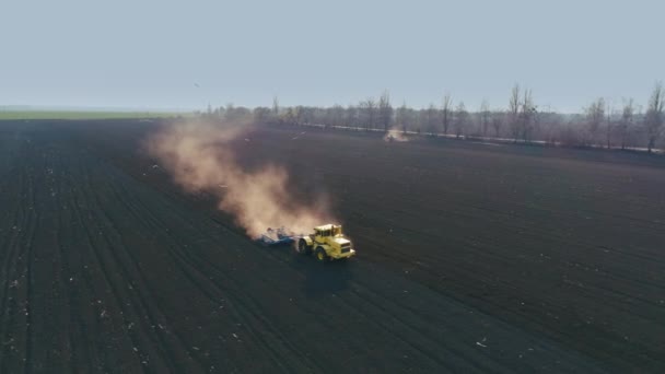 Tracteur dans le grand champ brun prépare le sol pour l'ensemencement. Vol autour 