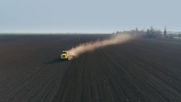 Tracteur dans le grand champ brun prépare le sol pour l'ensemencement. Vue de face 