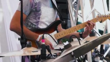 Gitarist arka plana odaklanan canlı bir performans sırasında bir rock grubunda bir elektro gitar çalıyor