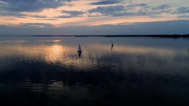 Yatlar gün batımında sakin suda seyir ile huzurlu sahnehavadan drone görüntüleri.