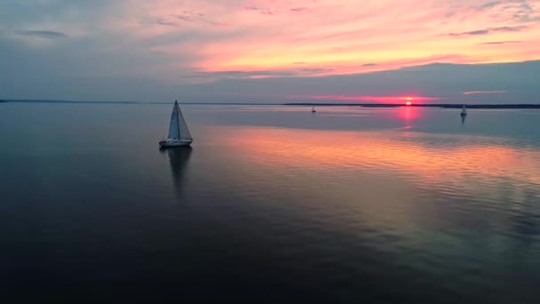 Aerial drone footage of peaceful scene with yacht cruising at calm water at dusk. — Stock Video