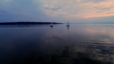 Yatlar gün batımında sakin suda seyir ile huzurlu sahnehavadan drone görüntüleri.