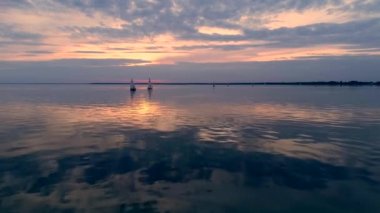 Yatlar gün batımında sakin suda seyir ile huzurlu sahnehavadan drone görüntüleri.