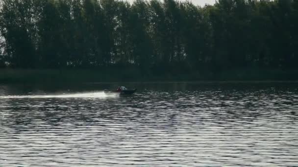 Person på liten fiskebåt trolling solo på Dnipro floden med skog bakgrund. Långsam rörelse skott — Stockvideo
