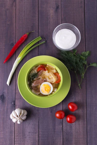 Zuppa di pollo con spaghetti fatti in casa e panna acida in un piatto sul tavolo di legno — Foto Stock