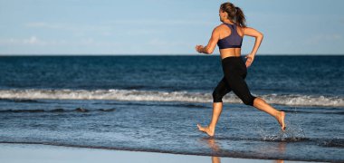Koşmak etkin sportif kadın bacaklarını ile su sıçramalarına su plaj güneş ve mavi gökyüzü, üzerinde çalışan