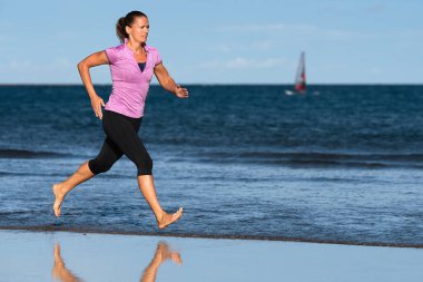 Koşmak etkin sportif kadın bacaklarını ile su sıçramalarına su plaj güneş ve mavi gökyüzü, üzerinde çalışan