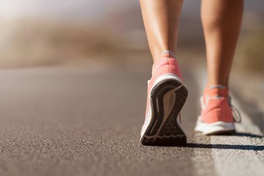 Spor ayakkabılarıyla koşan bir kadının koşu ayakkabısı.