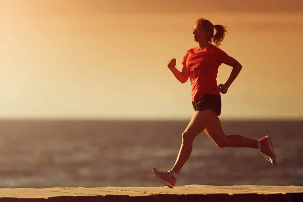 Woman running on beach in morning sunrise, fitness workout sport