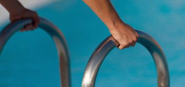 Yüzme havuzunda tırabzan tutan bir kadın eli