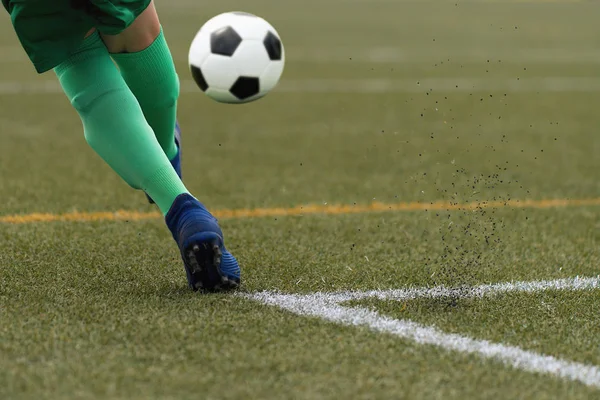 Foot of a child football player and ball on the football field