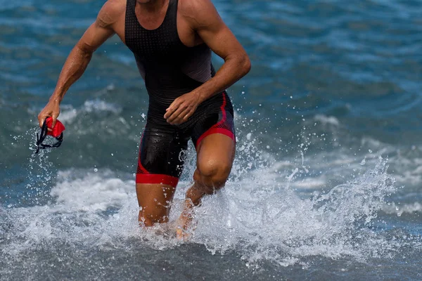 Triatlet yüzücü okyanus yüzme yarışı bitirme dışarı çalışan. Fit adam ironman için profesyonel triatlon takım su dışında belirlenen yüzme sprint biten