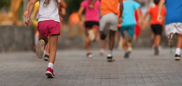 Running children, young athletes run in a kids run race,running on city road detail on legs