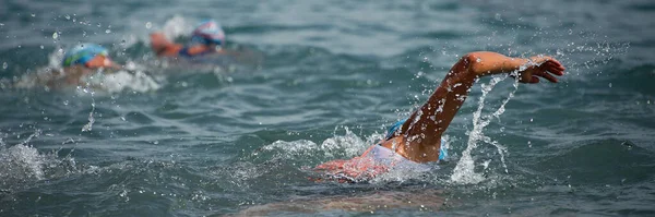 Competitors swimming out into open water at the beginning of triathlon