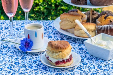 İkindi çayı kek ve çilek reçeli ve kaymak bahçe içinde bir tablo set up ile geleneksel İngiliz çörekler. Açık havada yemek.