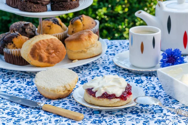 İkindi çayı kek ve çilek reçeli ve kaymak bahçe içinde bir tablo set up ile geleneksel İngiliz çörekler. Açık havada yemek.