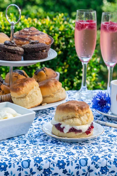 İkindi çayı kek ve çilek reçeli ve kaymak bahçe içinde bir tablo set up ile geleneksel İngiliz çörekler. Açık havada yemek.