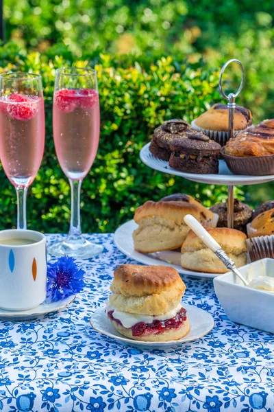 İkindi çayı kek ve çilek reçeli ve kaymak bahçe içinde bir tablo set up ile geleneksel İngiliz çörekler. Açık havada yemek.
