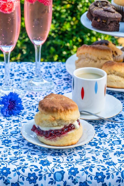 İkindi çayı kek ve çilek reçeli ve kaymak bahçe içinde bir tablo set up ile geleneksel İngiliz çörekler. Açık havada yemek.