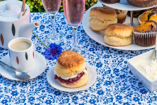 İkindi çayı kek ve çilek reçeli ve kaymak bahçe içinde bir tablo set up ile geleneksel İngiliz çörekler. Açık havada yemek.