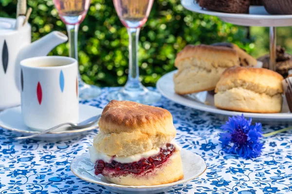 İkindi çayı kek ve çilek reçeli ve kaymak bahçe içinde bir tablo set up ile geleneksel İngiliz çörekler. Açık havada yemek.