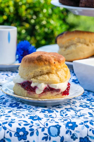 İkindi çayı kek ve çilek reçeli ve kaymak bahçe içinde bir tablo set up ile geleneksel İngiliz çörekler. Açık havada yemek.