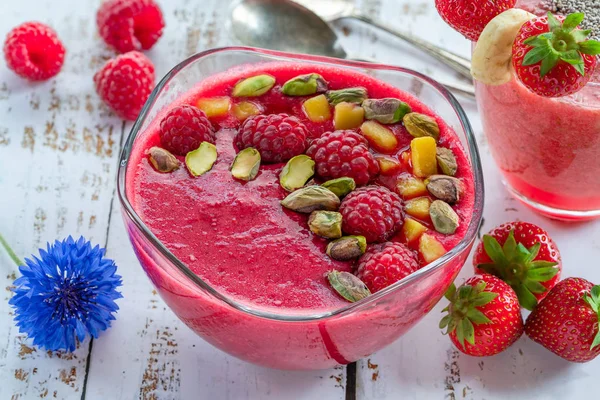 Ahududu ve çilek smoothies taze meyve ve antep fıstığı ile süslenmiş. Sağlıklı kahvaltı fikir.