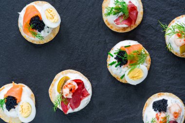 Somon, tedavi bresaola, kerevit, havyar, bıldırcın yumurtası ve ekşi krema - gurme parti gıda - üstten görünüm ile kokteyl blinis yelpazesi